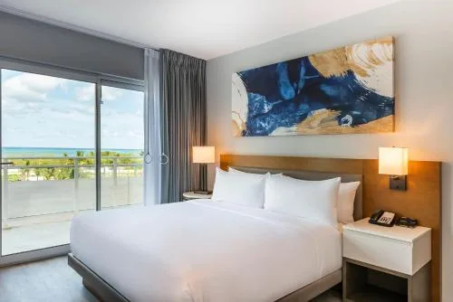 King bed and balcony in a mobility accessible one-bedroom suite at Embassy Suites Aruba Beach Resort.
