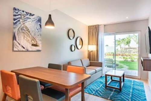Suite sitting room with blue rug and outdoor patio view at Embassy Suites Aruba Beach Resort.