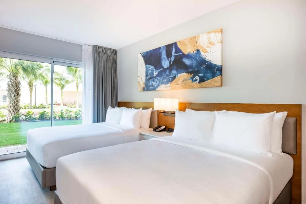 Two-bed suite bedroom with patio view at Embassy Suites Aruba Beach Resort.