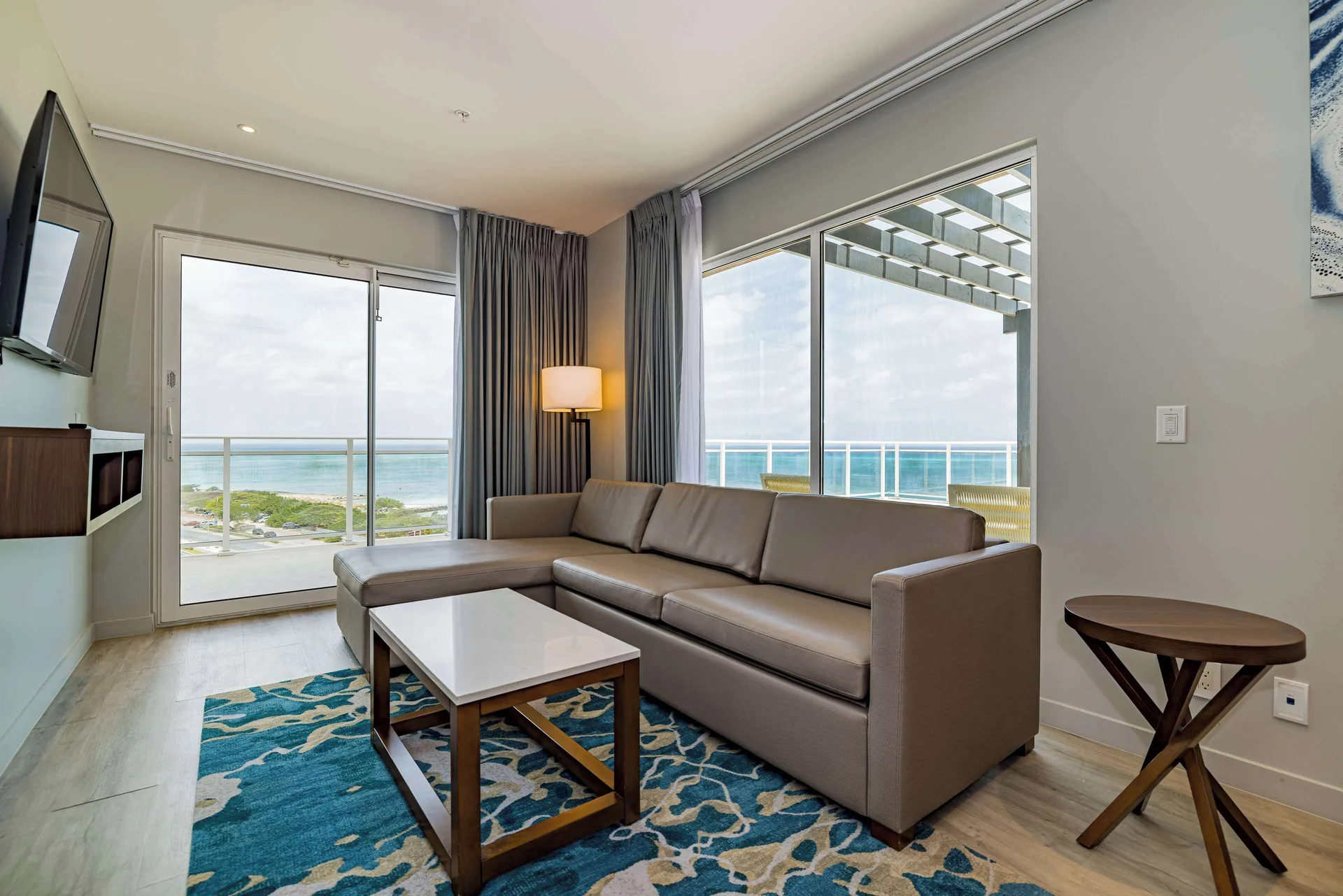 Oceanfront living room with sofa and balcony view at Embassy Suites Aruba Beach Resort.