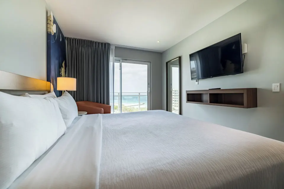 Suite Ocean Front Balcony bedroom with king bed and ocean view at Embassy Suites Aruba Beach Resort.