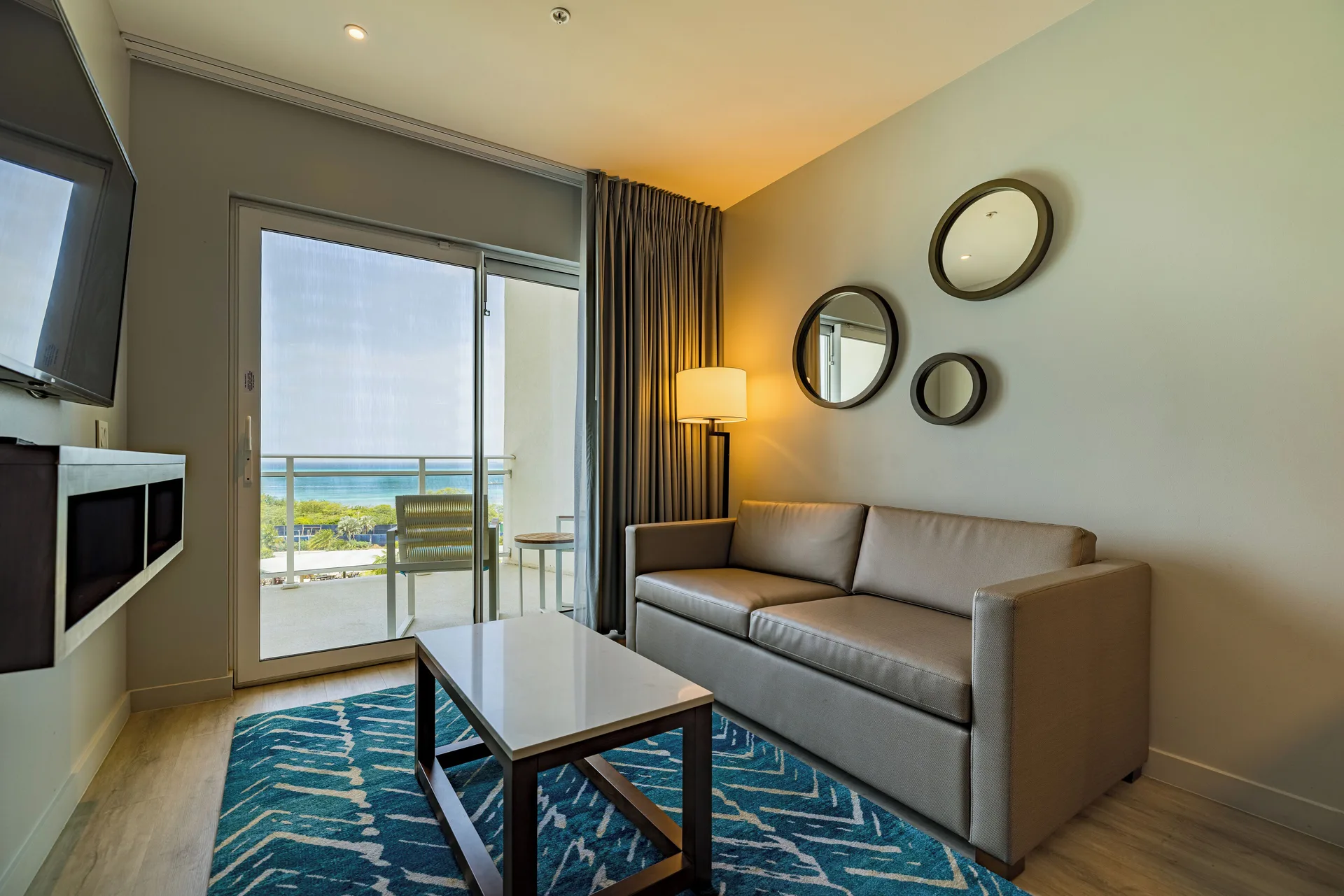 Ocean front balcony suite living room with sofa at Embassy Suites Aruba Beach Resort.