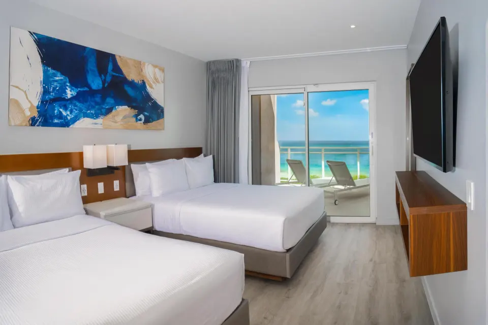 Ocean front balcony suite bedroom with two beds at Embassy Suites Aruba Beach Resort.