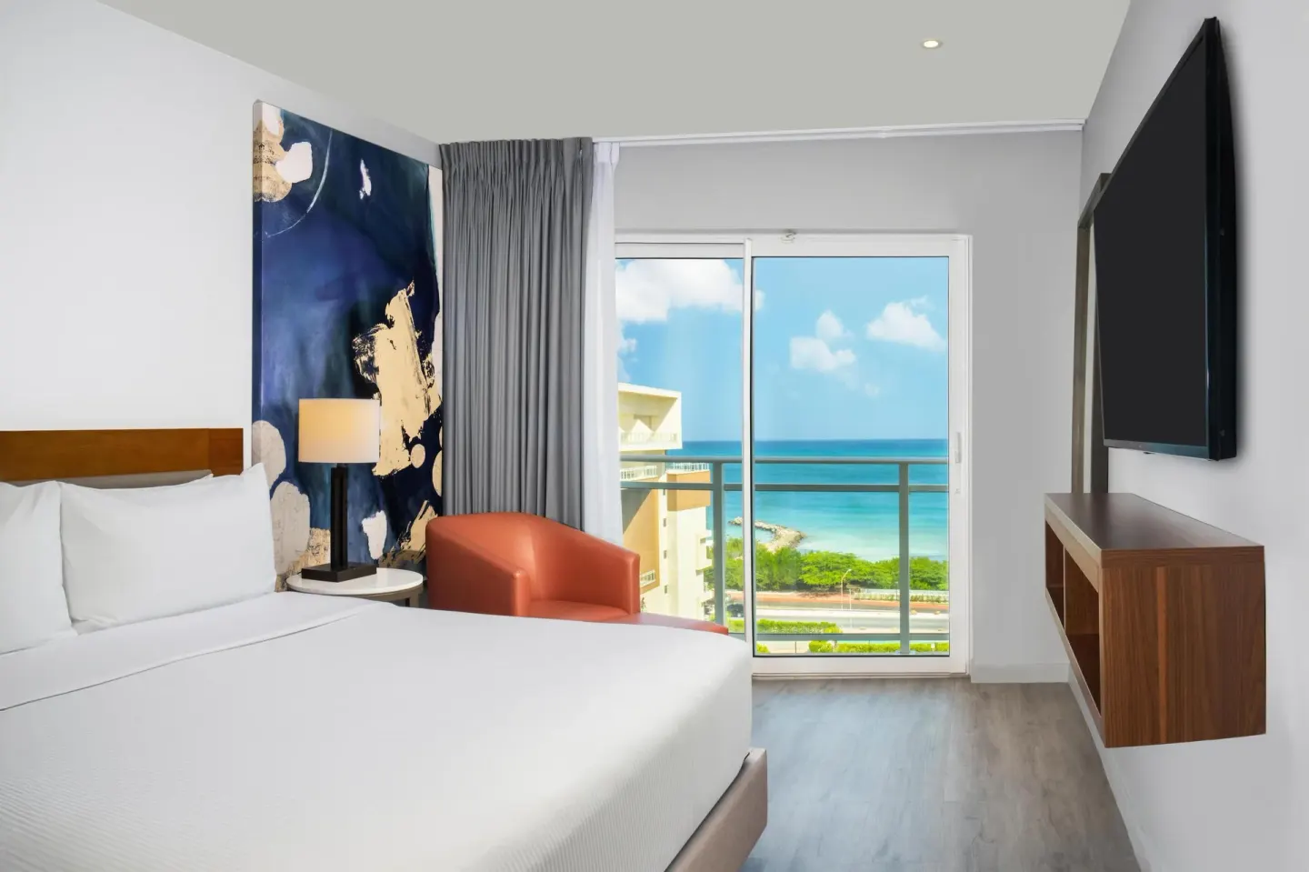 Ocean-view one-bedroom suite with king bed and balcony at Embassy Suites Aruba Beach Resort.