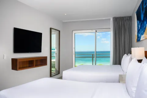 Ocean-view one-bedroom suite with two beds and balcony at Embassy Suites Aruba Beach Resort.