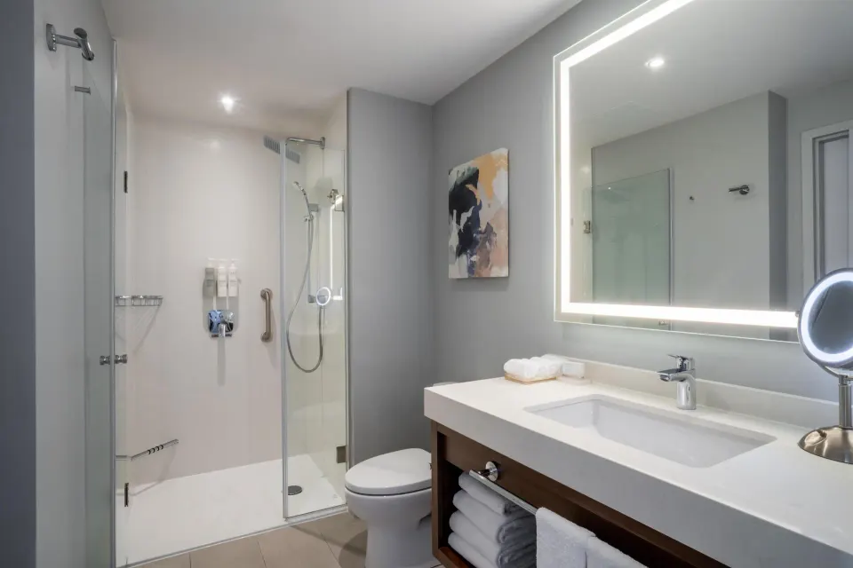 Bathroom with glass shower and lighted mirror at Embassy Suites Aruba Beach Resort.