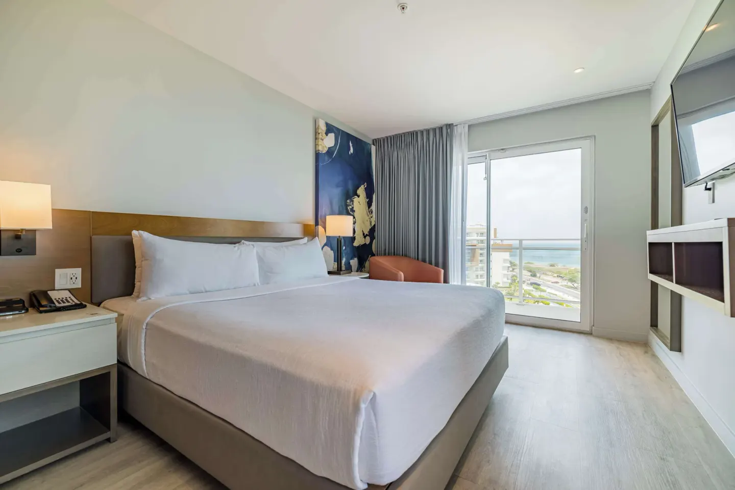 King bedroom with balcony view in a suite at Embassy Suites Aruba Beach Resort.