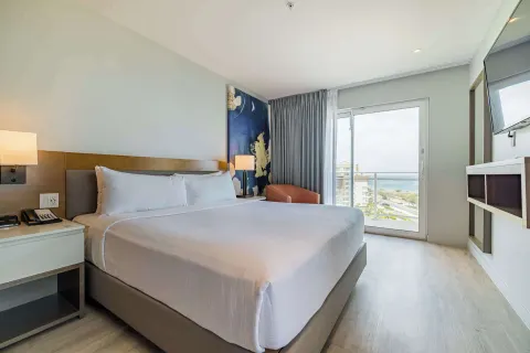 King bedroom with balcony view in a suite at Embassy Suites Aruba Beach Resort.