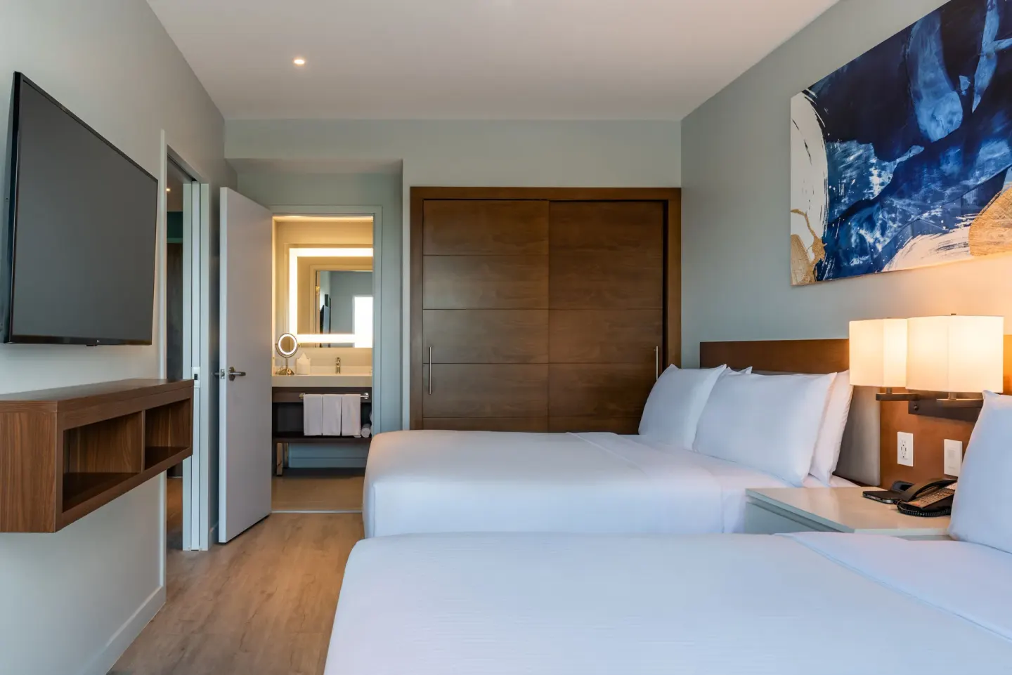 Two-bed bedroom with TV and bath entry at Embassy Suites Aruba Beach Resort.