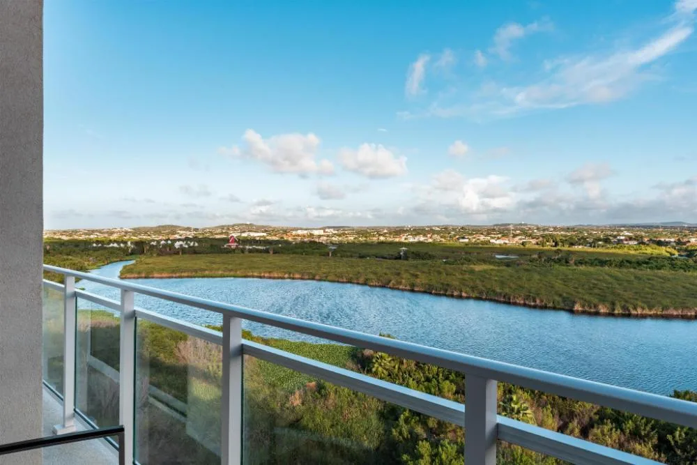 Balcony view over water and greenery at Embassy Suites Aruba Beach Resort.