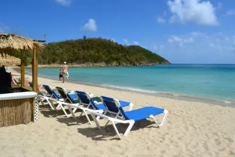 Blue lounge chairs and a thatched shade on the beach at Emerald Beach Resort.