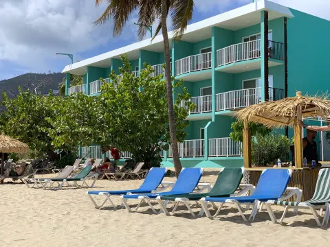 Beach loungers and thatched shade sit in front of turquoise balconies at Emerald Beach Resort.