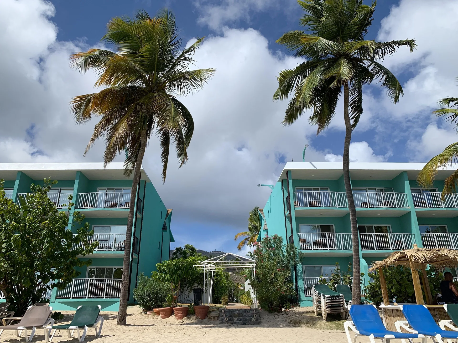 Turquoise guest buildings and palm trees rise behind the beach at Emerald Beach Resort.