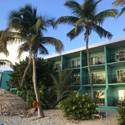 Palm trees frame turquoise guestroom balconies and sandy beach loungers at Emerald Beach Resort.