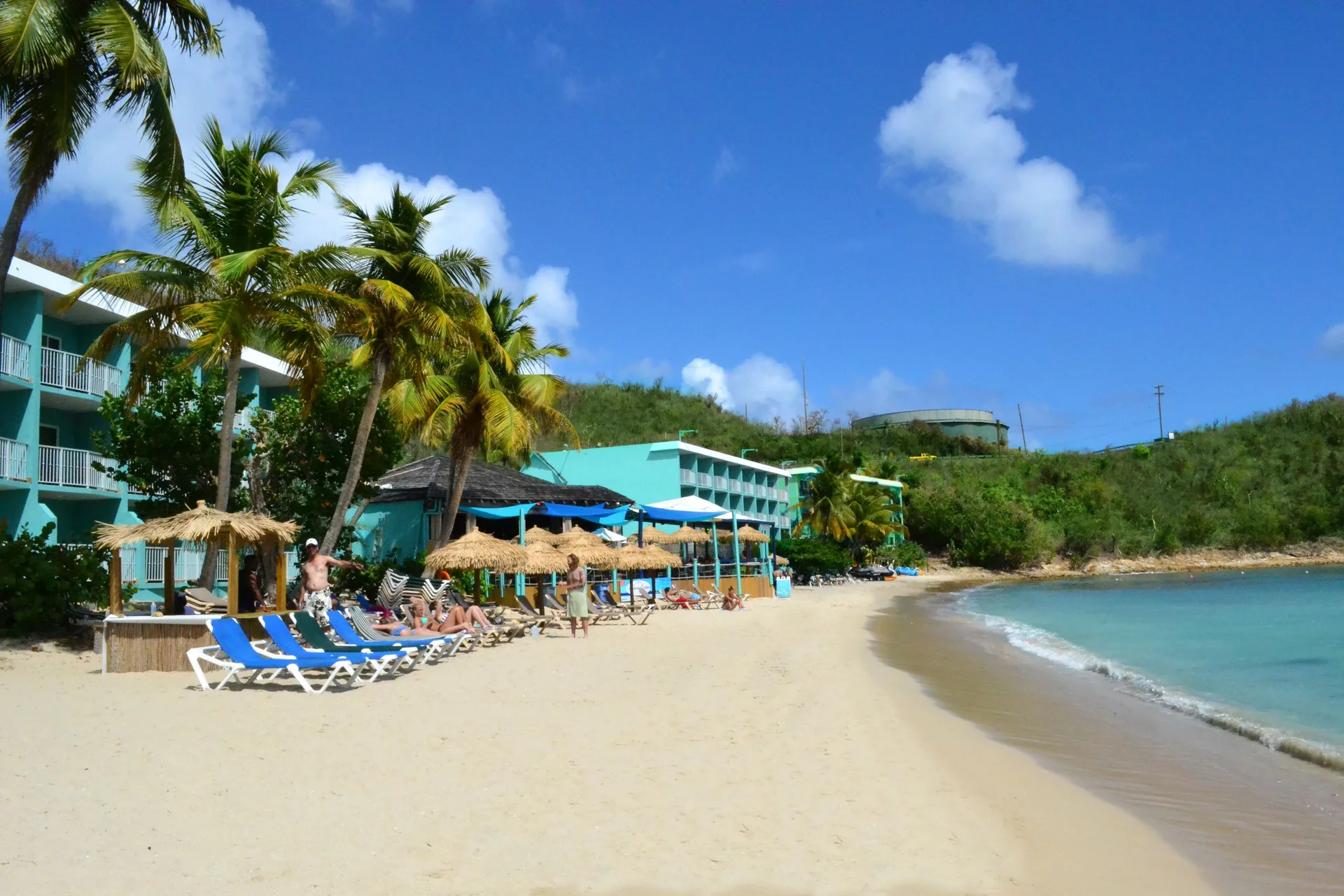 Palm-lined beachfront with loungers and turquoise resort buildings at Emerald Beach Resort.