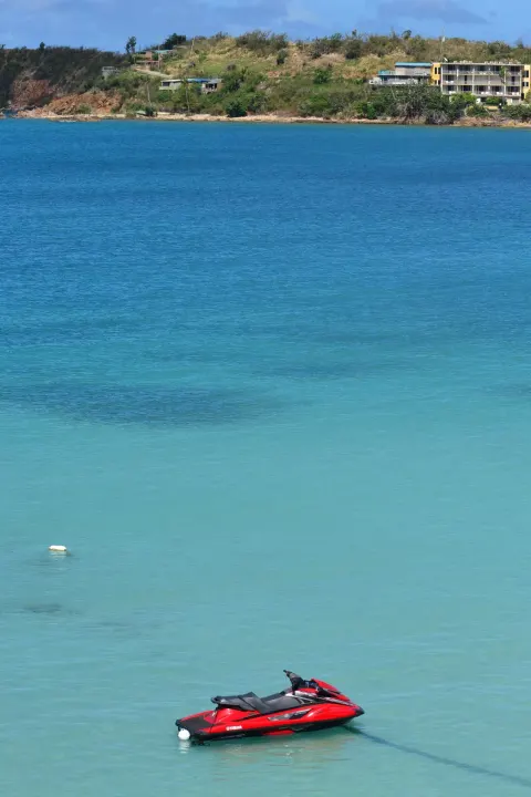 Red personal watercraft floating in turquoise bay water at Emerald Beach Resort.