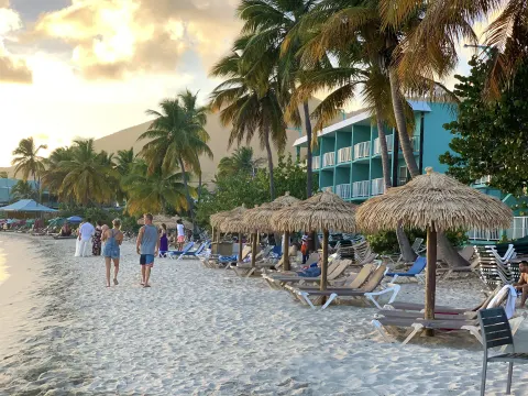 Beach loungers, thatched umbrellas, palms, and resort buildings at Emerald Beach Resort.