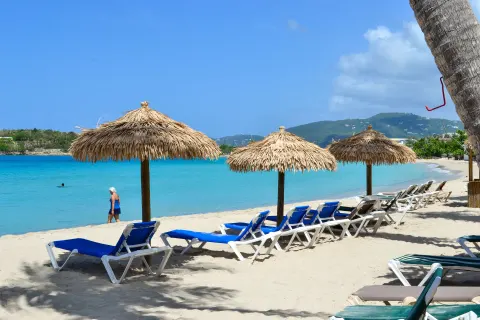 Thatched umbrellas and blue beach loungers facing the bay at Emerald Beach Resort.