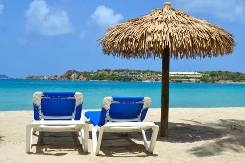 Two blue lounge chairs beneath a thatched umbrella at Emerald Beach Resort.