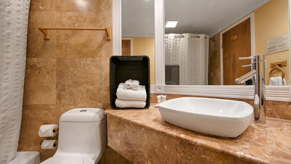 Bathroom with vessel sink, toilet, towels, and shower curtain at Emerald Beach Resort.