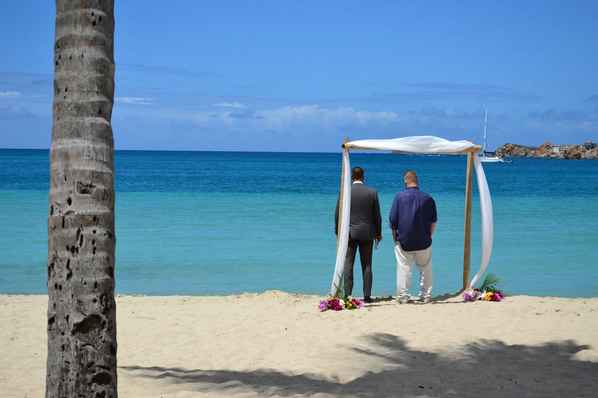 Two people stand beneath a beach ceremony arch at Emerald Beach Resort.