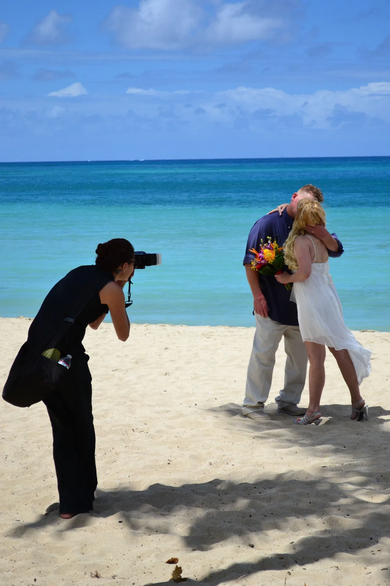 Couple posing for a beach photo shoot by turquoise water at Emerald Beach Resort.