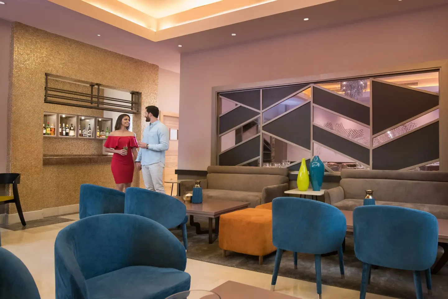 Lobby lounge with blue chairs and a small bar at Emotions by Hodelpa Puerto Plata.