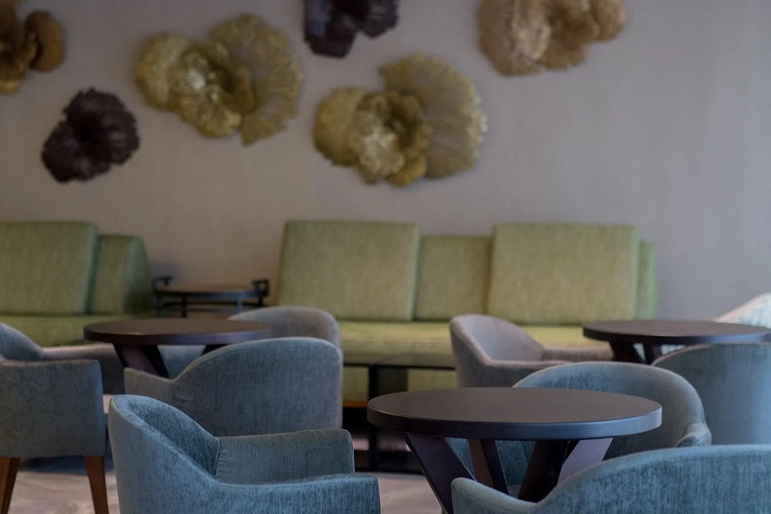 Lounge seating with blue chairs and floral wall decor at Emotions by Hodelpa Puerto Plata.