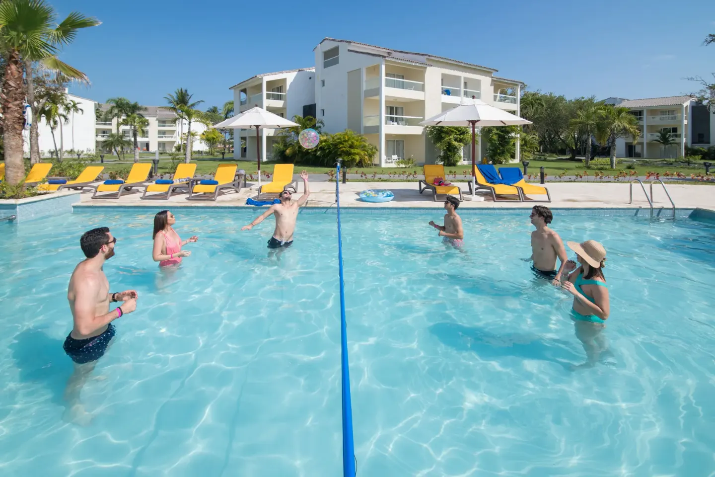 Guests play volleyball in a resort pool at Emotions by Hodelpa Puerto Plata.