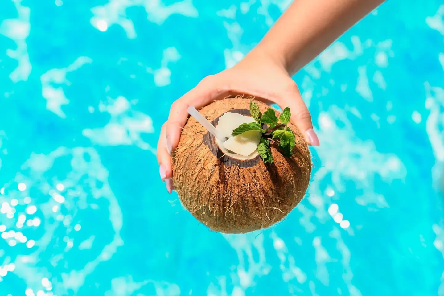 Hand holding a coconut drink over the pool at Emotions by Hodelpa Puerto Plata.
