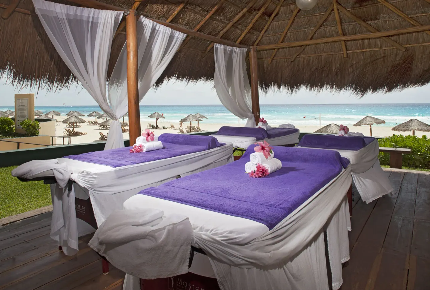 Beach massage tables under a thatched palapa facing the sea at Emporio Cancun.