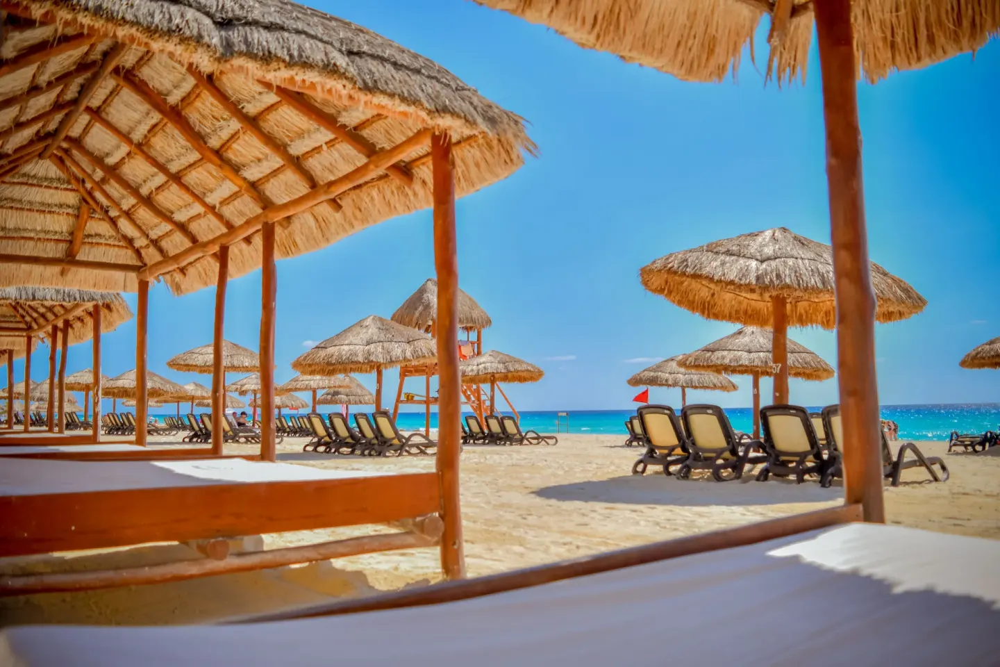 Beach palapas and lounge chairs facing the turquoise sea at Emporio Cancun.