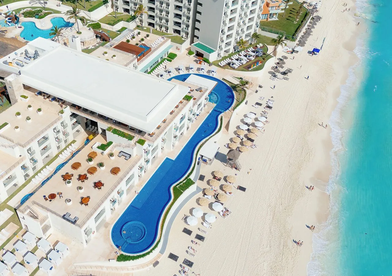 Aerial view of beachfront pools, umbrellas, and turquoise water at Emporio Cancun.