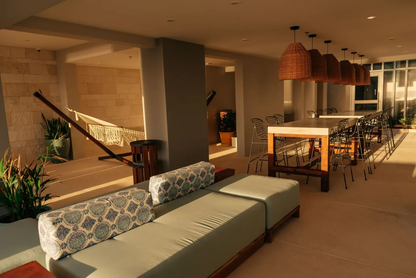 Covered lounge area with sofas, hammock, and communal table at Emporio Cancun.