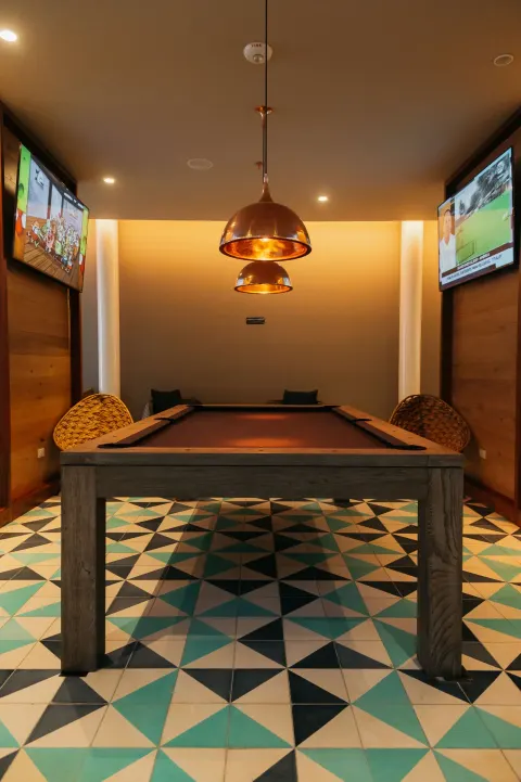 Game room with a pool table, pendant lights, and wall-mounted TVs at Emporio Cancun.
