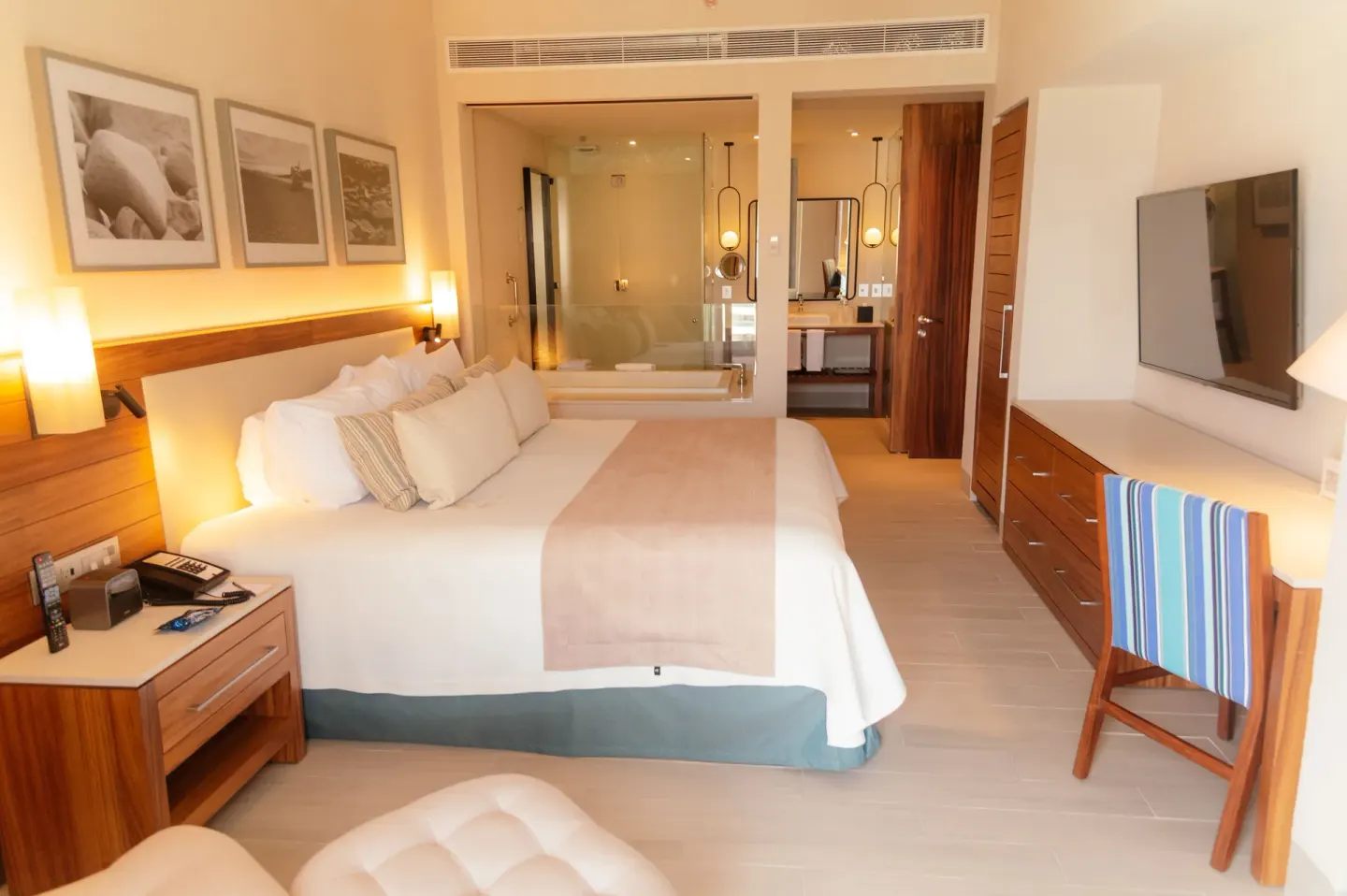Guest room with one king bed, wall-mounted TV, desk, and glass bathroom at Emporio Cancun.