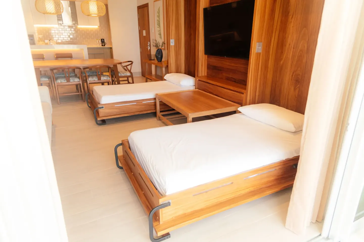 Guest room lounge with two daybeds, TV wall, dining table, and kitchen at Emporio Cancun.