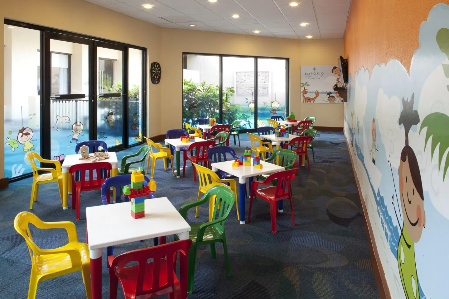 Kids club room with colorful chairs, activity tables, toys, and wall murals at Emporio Cancun.