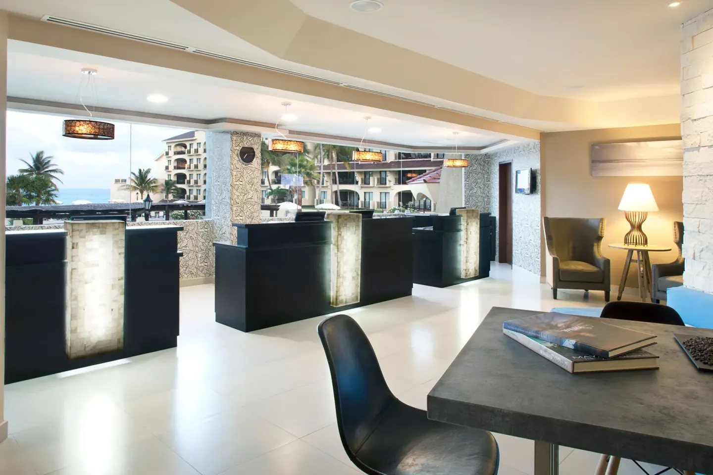 Lobby reception desks with illuminated fronts and ocean-facing windows at Emporio Cancun.