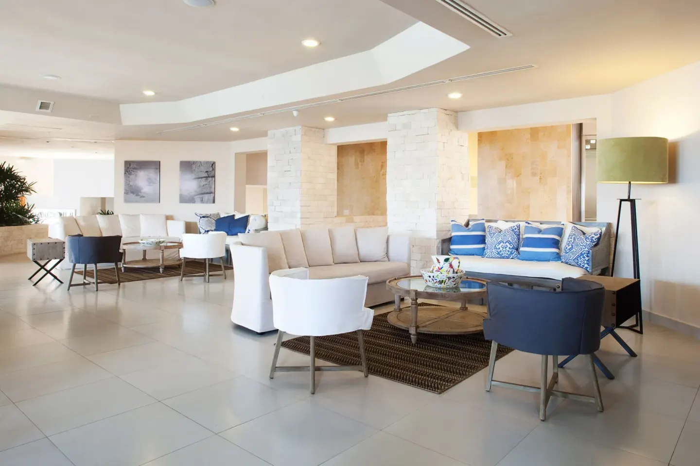 Lobby seating area with sofas, lounge chairs, and blue accent pillows at Emporio Cancun.