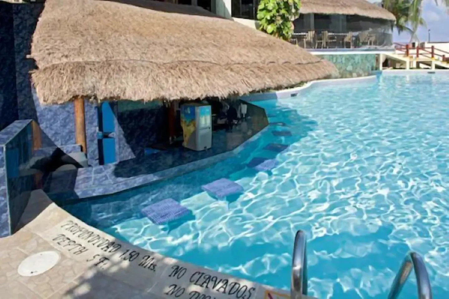 Pool with thatched swim-up bar area and turquoise water at Emporio Cancun.