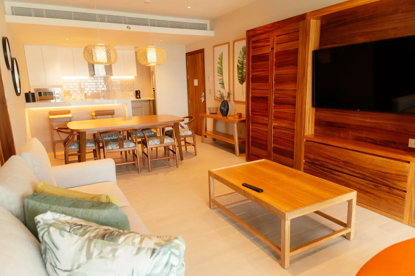 Suite living area with sofa, dining table, kitchenette, and wall-mounted TV at Emporio Cancun.