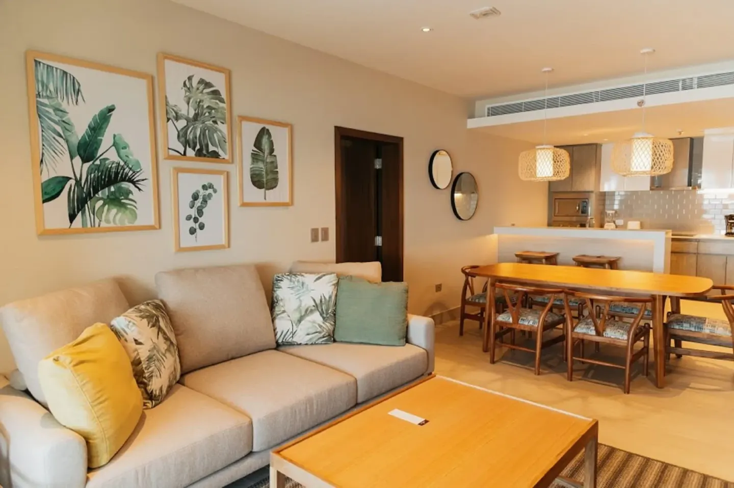 Suite living room with sofa, botanical artwork, dining table, and kitchen at Emporio Cancun.
