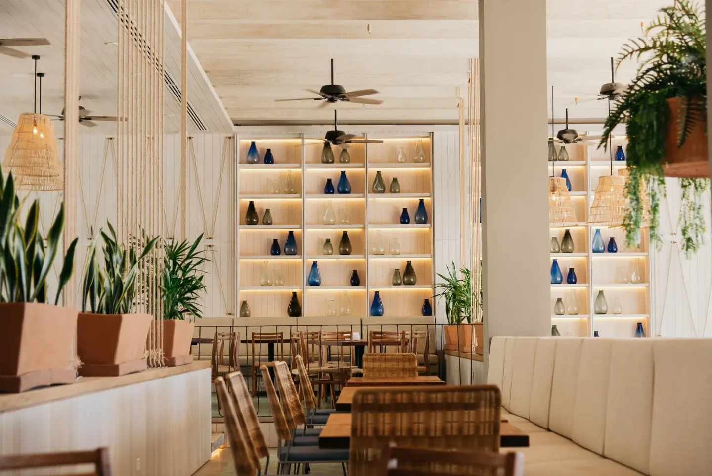 Dining room with illuminated shelves and woven chairs at Emporio Cancun.