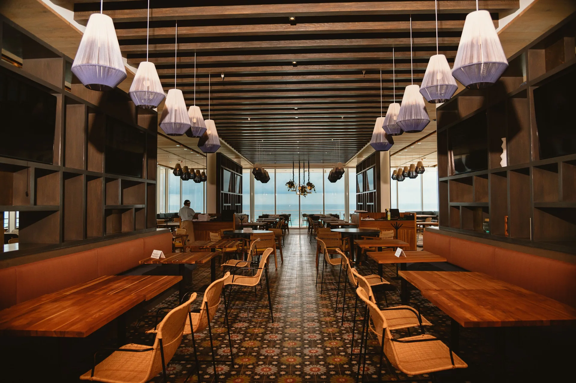 Large dining room with wooden tables and ocean-facing windows at Emporio Cancun.