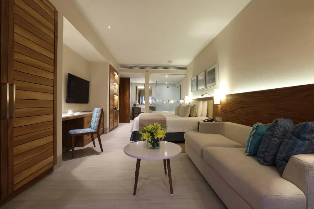 Deluxe Suite with bed, sofa, desk and warm wood accents at Emporio Cancun.