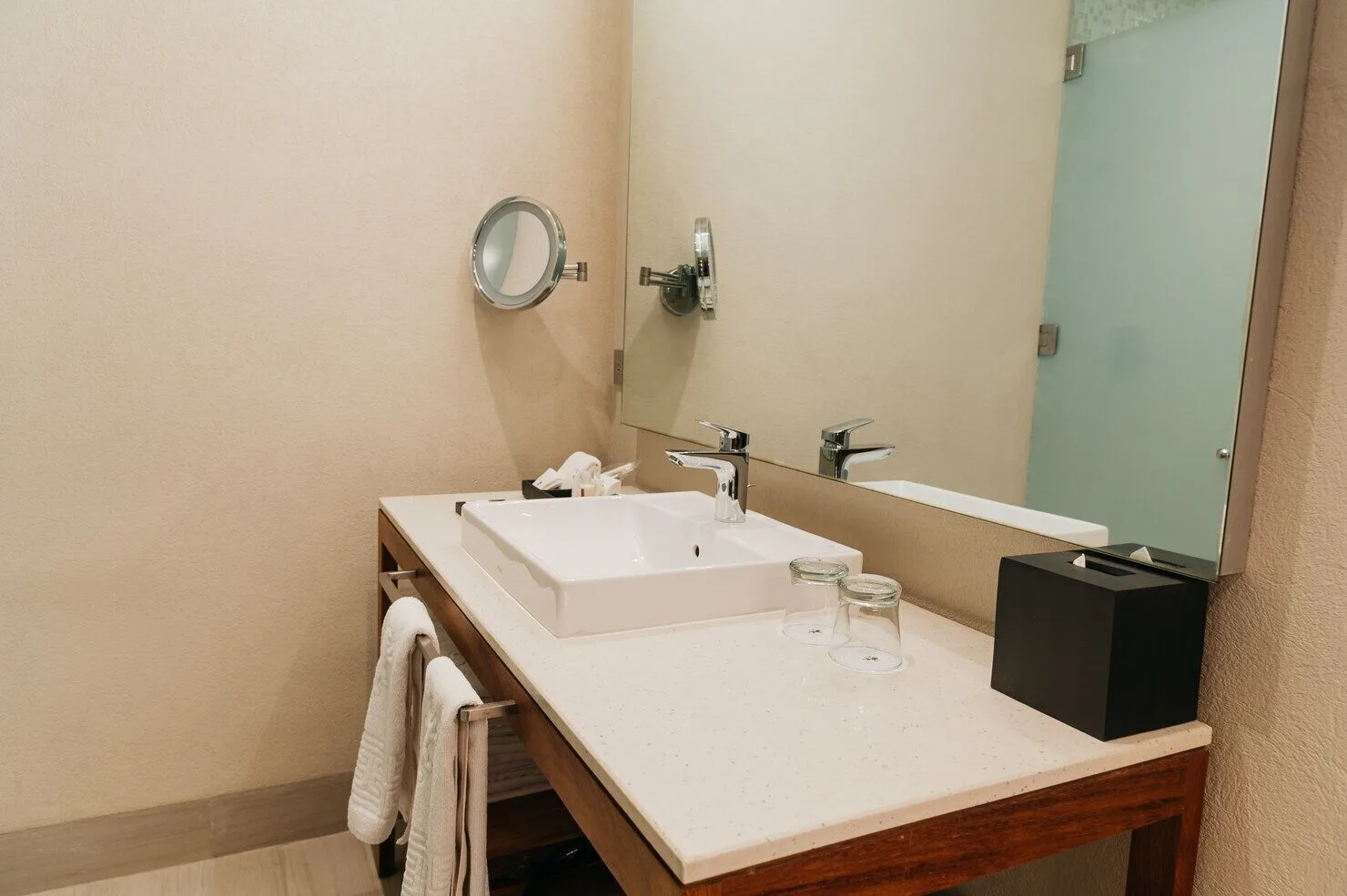Super Saver room bathroom vanity with sink, mirror, towels, and glasses at Emporio Cancun.