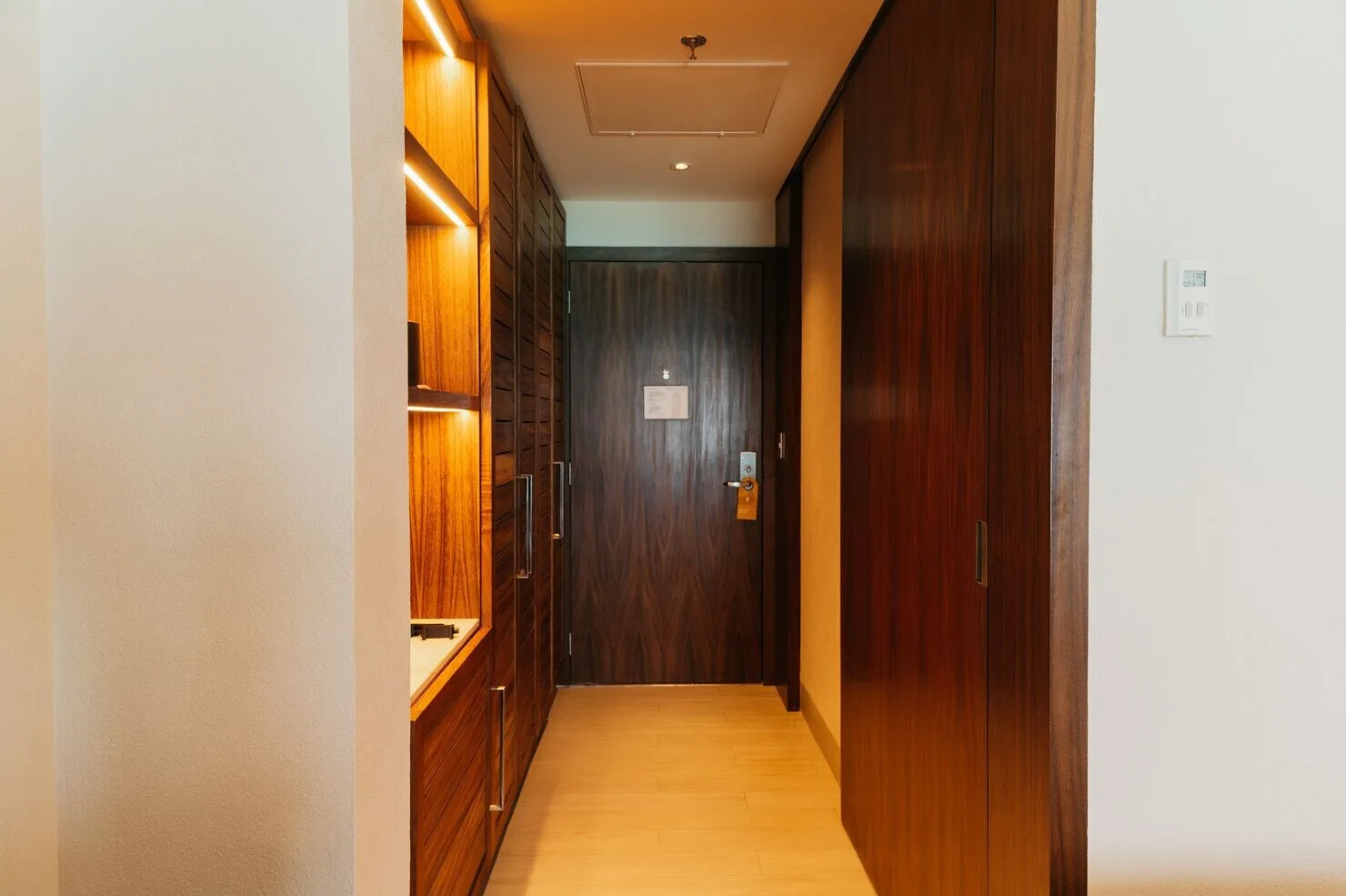 Super Saver room entry hall with wood closets, shelves, and door at Emporio Cancun.