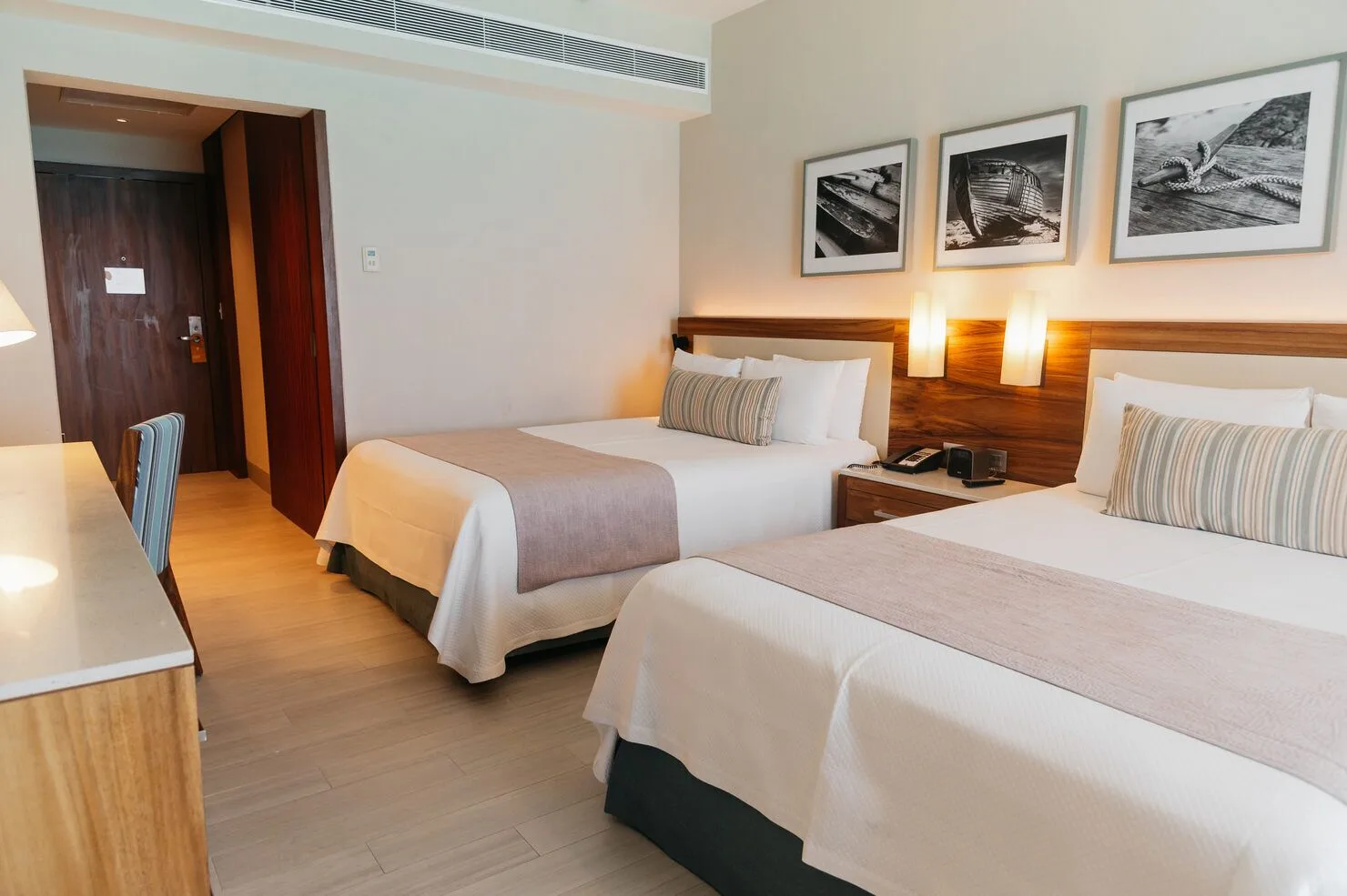 Super Saver room with two beds, desk edge, bedside lamps, and wall art at Emporio Cancun.