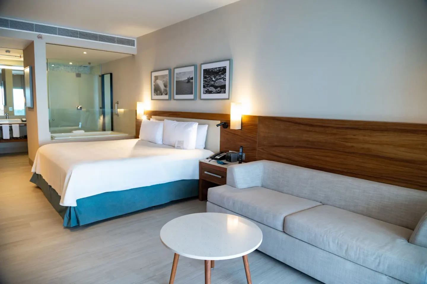 Swim Up Oceanfront room at Emporio Cancun with king bed, sofa, round table, and open bathroom area.